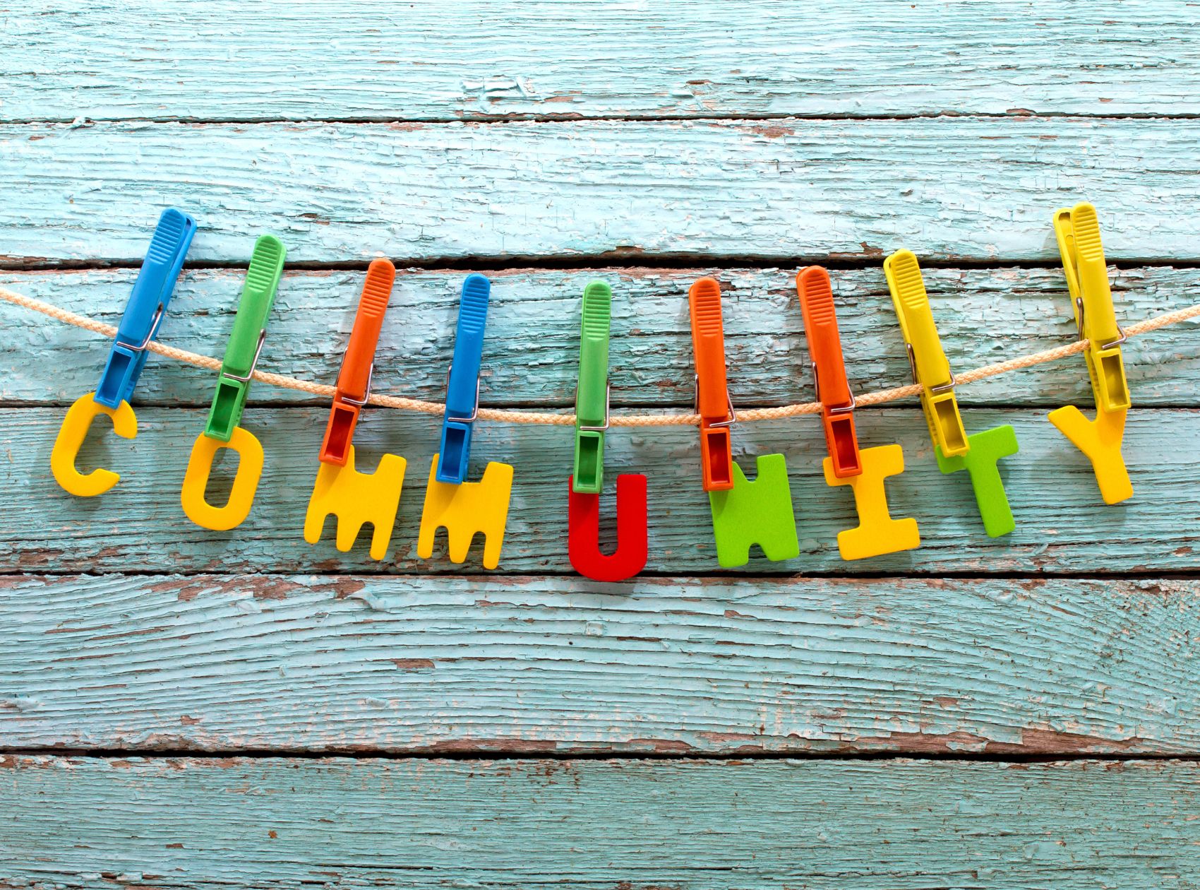 This is an image of the word "community" spelled out in colorful letters hanging by clothes pins on a clothes line.