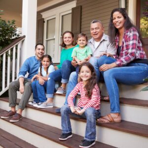 This image shows a multi generational family sitting on the stairs of the front porch of a house.