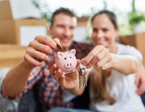 This is an image of a man holding a piggy bank and a woman holding a set of keys.